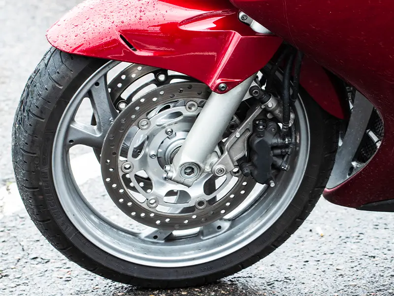 Pneu moto monté sur roue avant avec système de freinage, service pneus moto chez Bomerée Pneus.