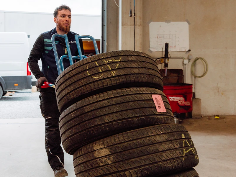 Technicien transportant plusieurs pneus dans l’atelier Bomerée Pneus à Montigny-le-Tilleul.