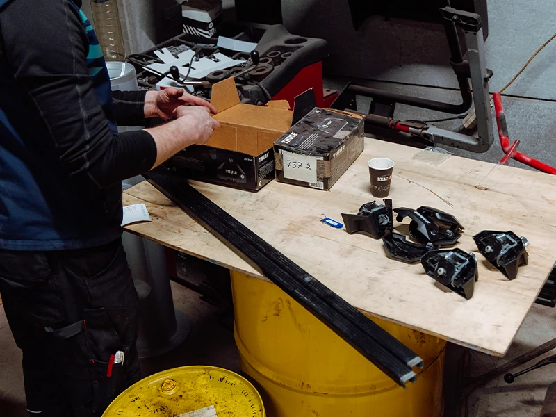 Préparation de barres de toit Thule sur une table d’atelier.